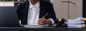 A solicitor writes notes at a desk while using a laptop to work on amputation compensation claims