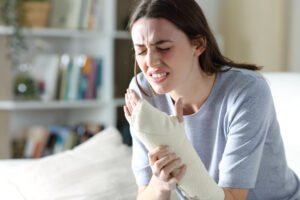 A woman holding her bandaged arm in pain after sustaining serious burn injuries.