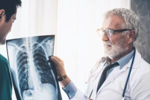 A radiologist is looking at an X-ray of a serious chest injury with his patient